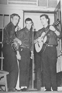 Three people singing into microphone