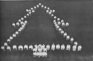 People posed in the shape of a christmas tree with an aerial photo.