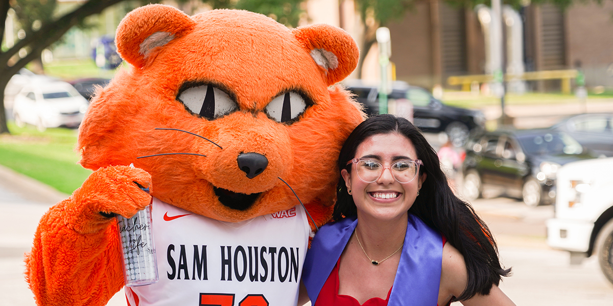 person smiling next to shsu mascot