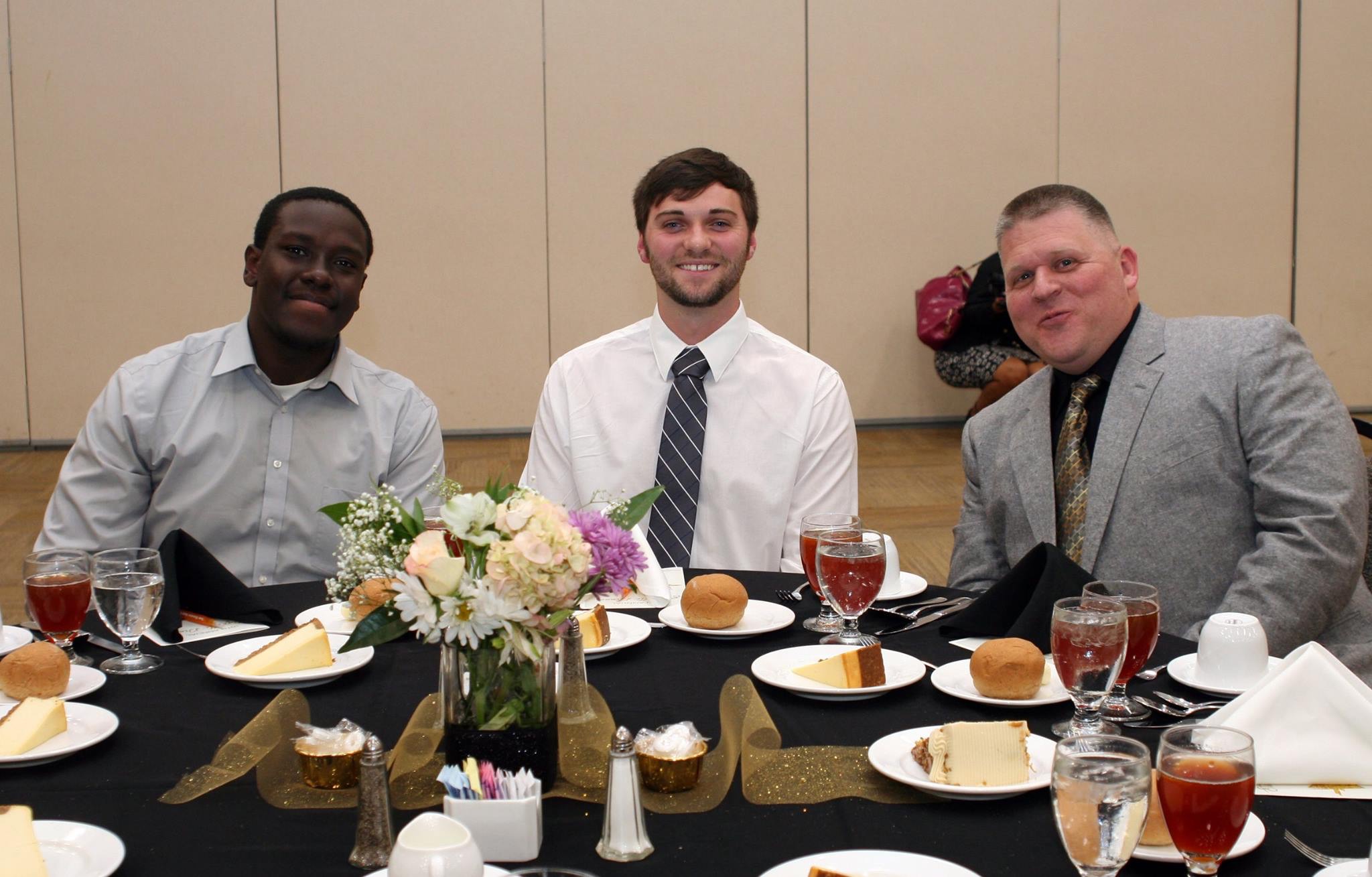 Three gentleman sit at a professionally set table.