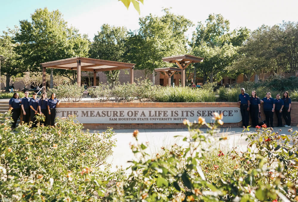 Wide shot of SGA members standing in front of the SHSU motto 