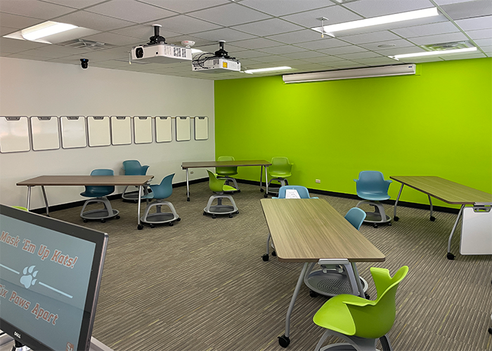 Evans 260, with three tables in view with colored rolling and spinning chairs at each table. A projector is diplaying the computer desktop on the wall.