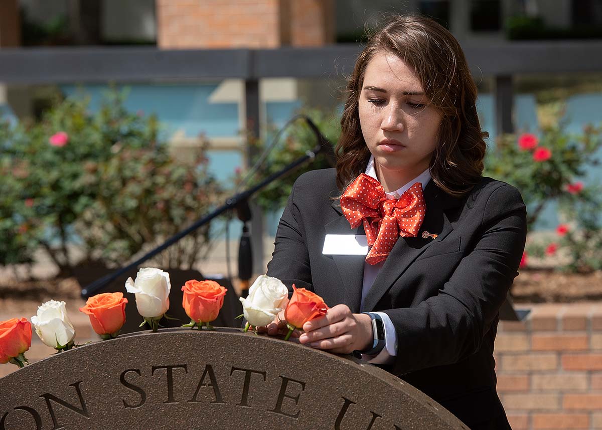 A student places a flower in the Raven's Call ceremonial arch.