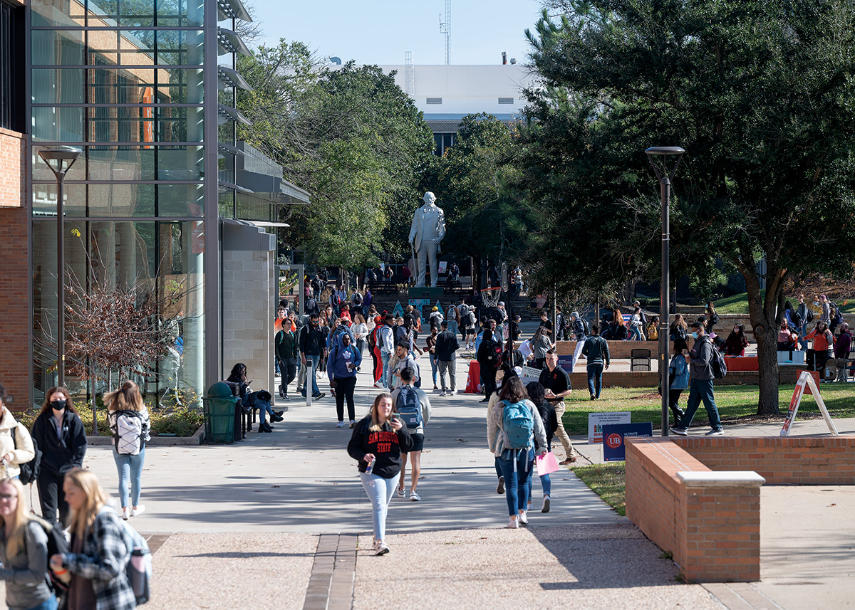 A view of the Frank Parker Plaza. The the left is the Lowman Student Center with its large glass entrance. Down the center is a view of the Newton Gresham Library and the miniature state of the Sam Houston. To the right are the beginnings of spaces where booths and tables are regularly set up.